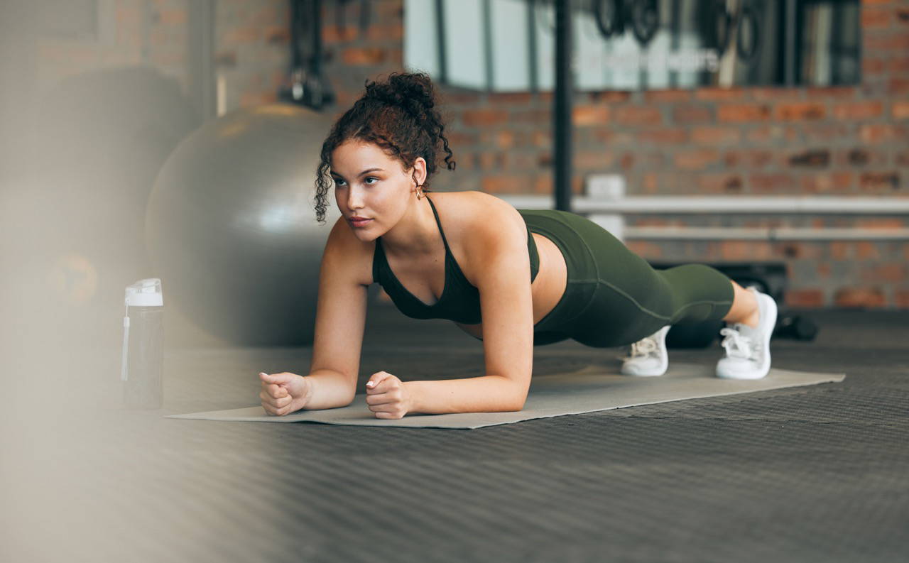 Fitness, gym and workout of a woman doing plank exercise or training for wellness with focus for healthy lifestyle. Female athlete with body weight routine for strong core, sports health and balance